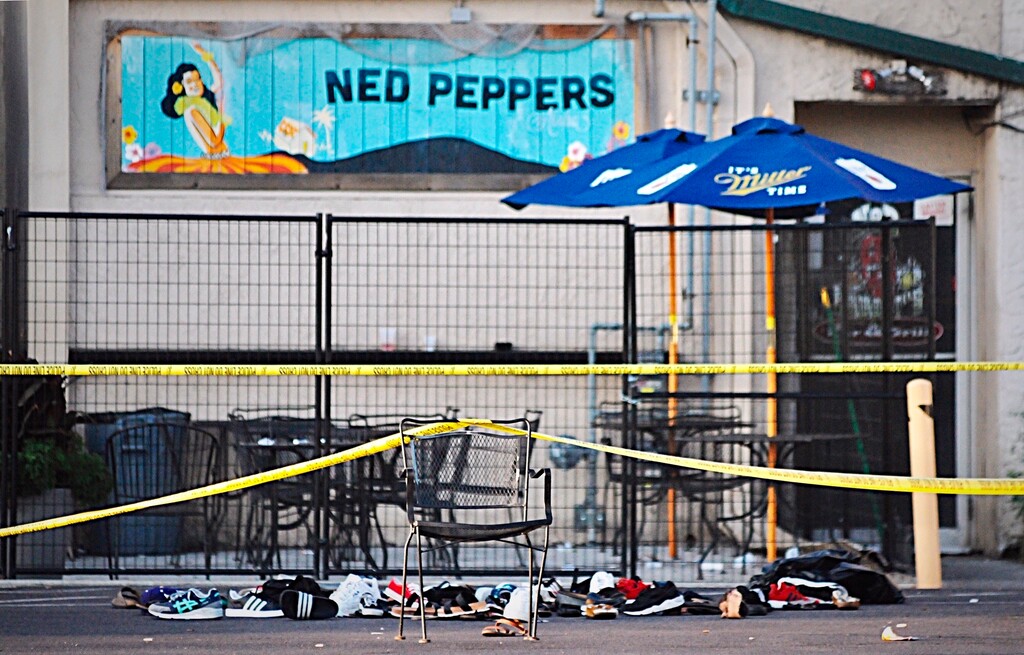 Police tape drapes over a chair near a pile of shoes after a mass shooting in Dayton, Ohio on Sunday, Aug, 4, 2019. (Marshall Gorby/Dayton Daily News via AP)