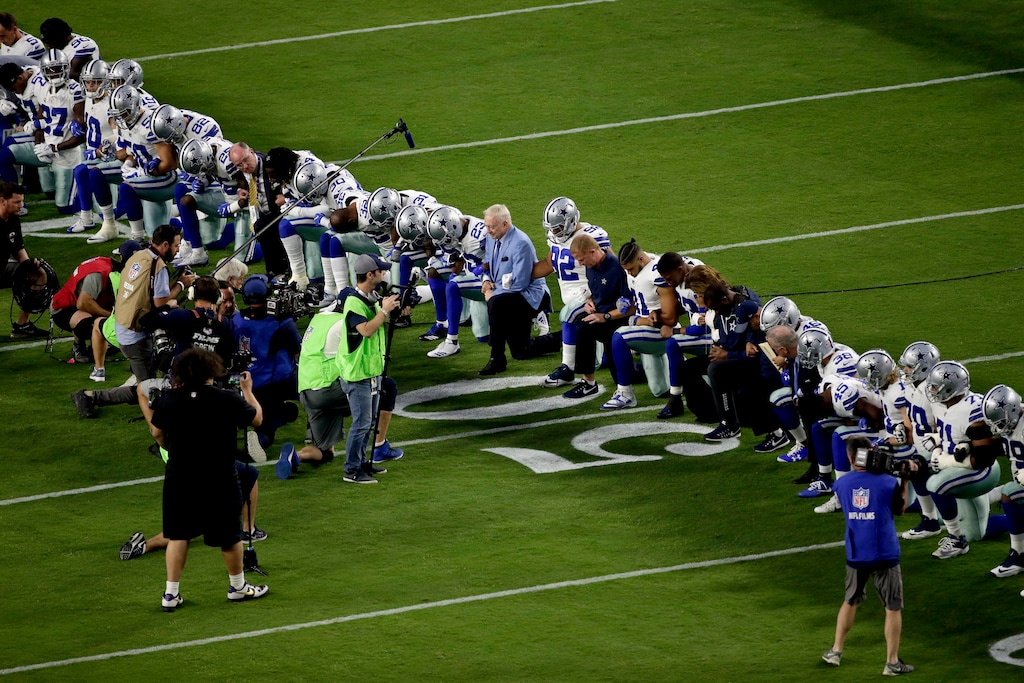The Dallas Cowboys, led by owner Jerry Jones, center, take a knee prior to the national anthem prior to an NFL football game against the Arizona Cardinals, Monday, Sept. 25, 2017, in Glendale, Ariz. (AP Photo/Matt York)