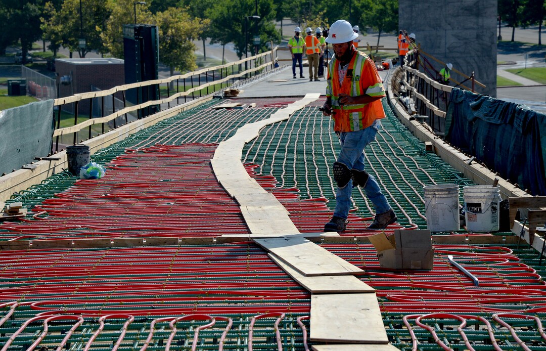 (Francisco Kjolseth  |  The Salt Lake Tribune) UDOT gives a tour of the state’s new longest pedestrian bridge on Thursday, August 20, 2020, connecting Utah Valley University in Orem to student housing and the community on the West side of I-15, as Mark Lubaski works on tubing. Crews are finishing up an extensive hydronic heating system that will pump warm water to keep the bridge clear of snow in the winters, as it gets ready to pour concrete for the walking surface. UDOT will close I-15 in both directions this weekend for work on the nearly 1,000 foot bridge that is 15 feet wide to accommodate pedestrians, cyclists and scooters. Elevators and stairs with small ramps to push up bicycles will be on each side of the bridge.
