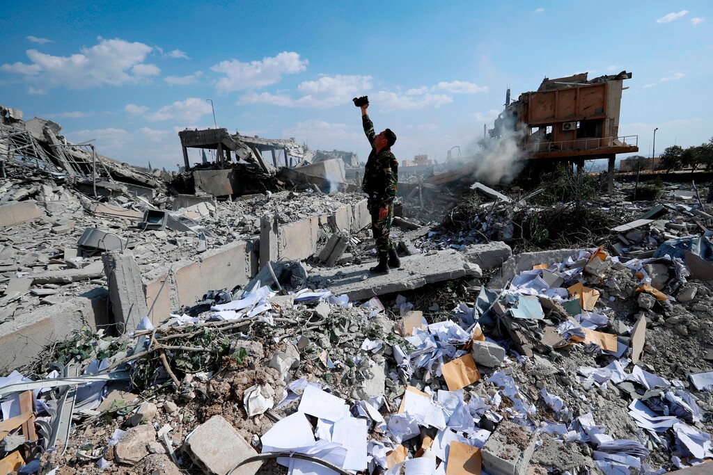 FILE - In this Saturday, April 14, 2018, file photo, a Syrian soldier films the damage of the Syrian Scientific Research Center, which was attacked by U.S., British and French military strikes to punish President Bashar Assad for suspected chemical attack against civilians, in Barzeh, near Damascus, Syria. (AP Photo/Hassan Ammar, File)