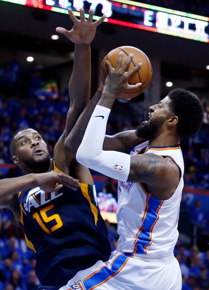 Oklahoma City Thunder forward Paul George, right, shoots as Utah Jazz forward Derrick Favors (15) defends in the first half of Game 1 of an NBA basketball first-round playoff series in Oklahoma City, Sunday, April 15, 2018. (AP Photo/Sue Ogrocki)
