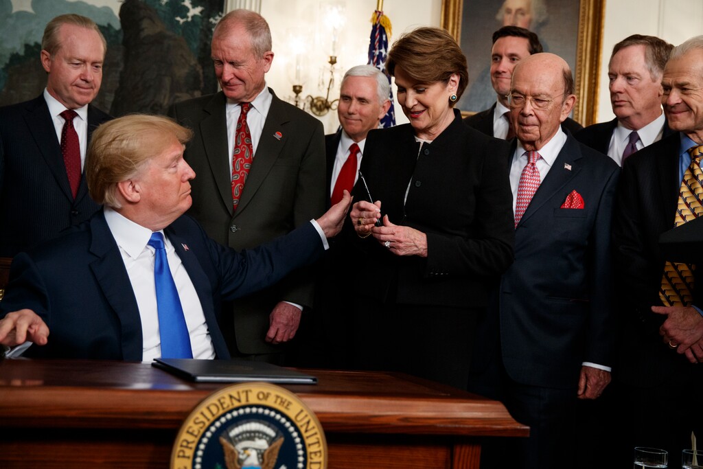President Donald Trump hands a pen to Lockheed Martin CEO Marillyn Hewson after signing a presidential memorandum imposing tariffs and investment restrictions on China, in the Diplomatic Reception Room of the White House, Thursday, March 22, 2018, in Washington. (AP Photo/Evan Vucci)