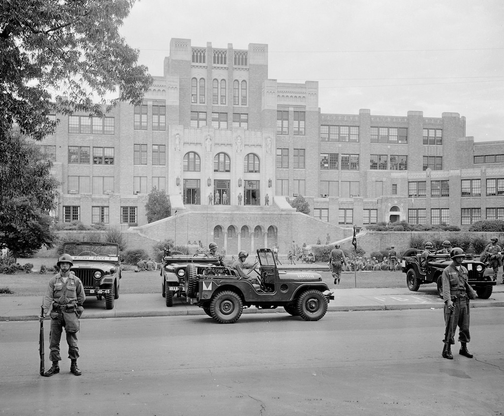 FILE - In this Sept. 26, 1957 file photo, members of the 101st Airborne Division take up positions outside Central High School in Little Rock, Ark. The troopers are on duty to enforce integration at the school. Officials said Wednesday, July 26, 2017, that newly unveiled plans to commemorate the 60th anniversary of nine African-American students desegregating Little Rock Central High School will reflect on the progress made in educating students of diverse backgrounds. (AP Photo, File)