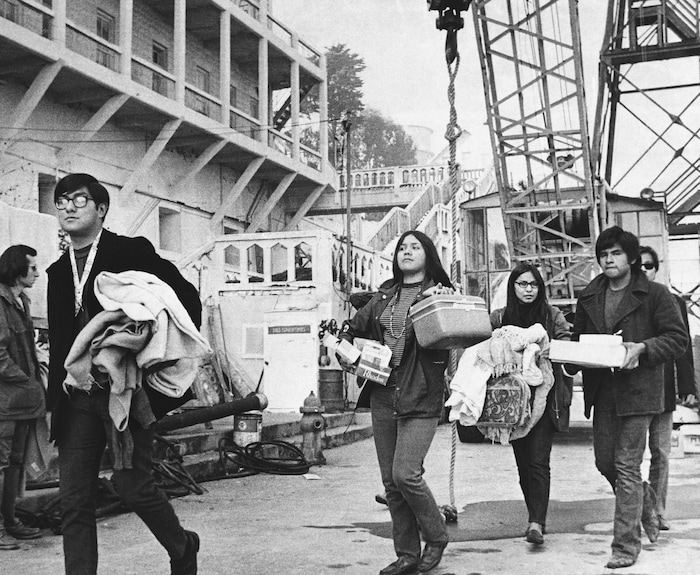 (RWK | AP file photo) In this Dec. 2, 1969, file photo, a new group of arrivals walks across the docking area with handfuls of possessions during the Native American occupation of Alcatraz Island in San Francisco. The week of Nov. 18, 2019, marks 50 years since the beginning of a months-long Native American occupation at Alcatraz Island in the San Francisco Bay. The demonstration by dozens of tribal members had lasting effects for tribes, raising awareness of life on and off reservations, galvanizing activists and spurring a shift in federal policy toward self-determination.