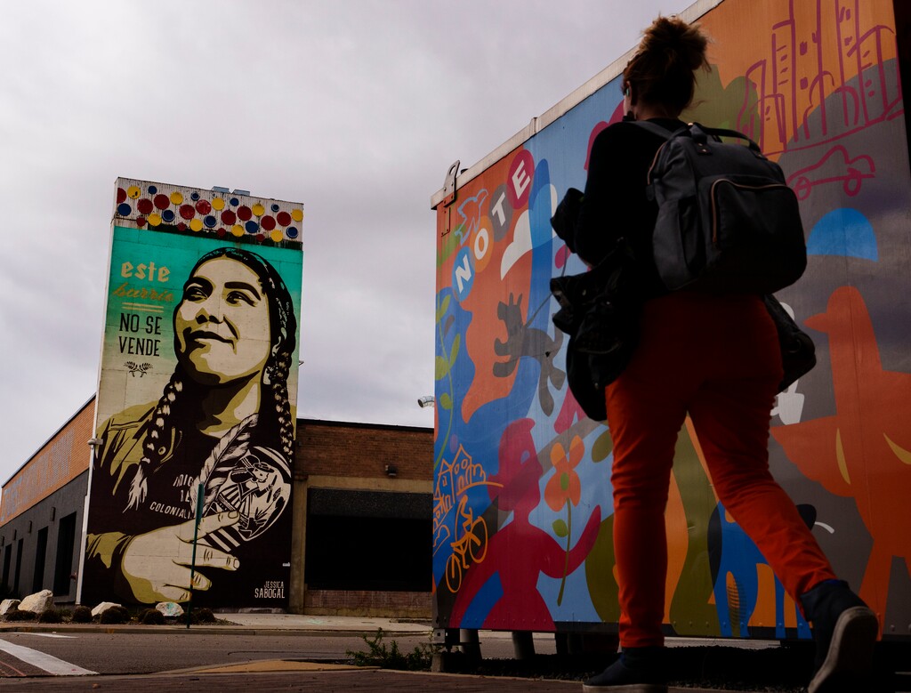 (Leah Hogsten | The Salt Lake Tribune) A woman walks past the mural on the side of the Furst Construction Co. at 700 West and North Temple. It says "Este Barrio No Se Vende" or "This Neighborhood is Not For Sale" by Colombian American artist Jessica Sabogal to represent the west side's fight against gentrification. The mural features an image of community activist Ella Mendoza.