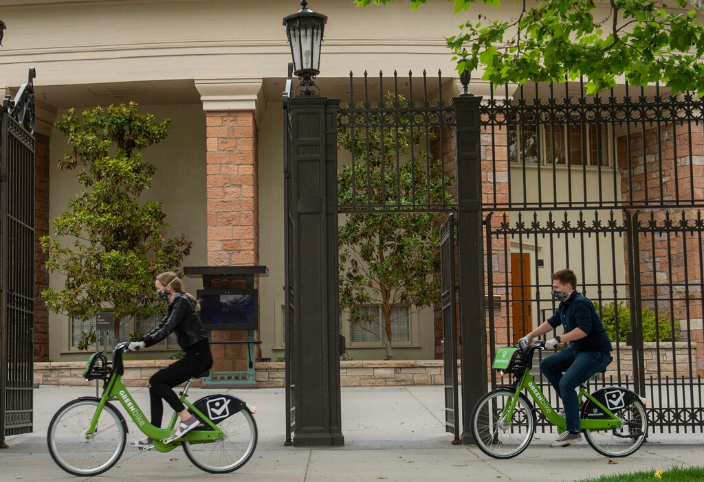 (Rick Egan  |  The Salt Lake Tribune)   Tourists wear masks as they ride bikes past the Tabernacle in Salt Lake CIty on Wednesday, May 20, 2020.