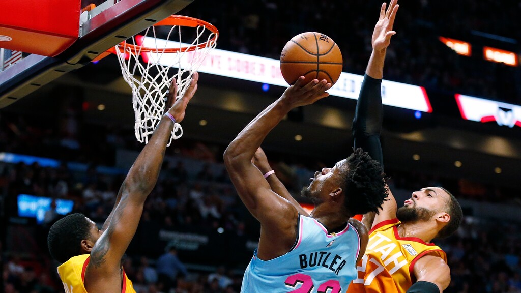 Miami Heat forward Jimmy Butler (22) goes to the basket between Utah Jazz forward Royce O'Neale (23) and center Rudy Gobert (27) during the first half of an NBA basketball game, Monday, Dec. 23, 2019, in Miami. (AP Photo/Joel Auerbach)