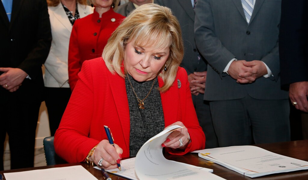 (Sue Ogrocki | The Associated Press) Oklahoma Gov. Mary Fallin signs revenue bills and a teacher pay raise bill in Oklahoma City, Thursday, March 29, 2018. On Friday, Fallin signed a bill that provides protections to faith-based agencies that won't place children in LGBT homes because of religious or moral convictions or policies.