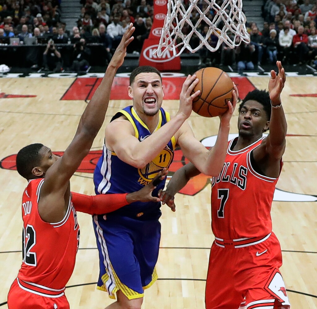 Golden State Warriors' Klay Thompson (11) shoots between Chicago Bulls' Kris Dunn (32) and Justin Holiday, right, during the second half of an NBA basketball game Wednesday, Jan. 17, 2018, in Chicago. The Warriors won 119-112. (AP Photo/Charles Rex Arbogast)