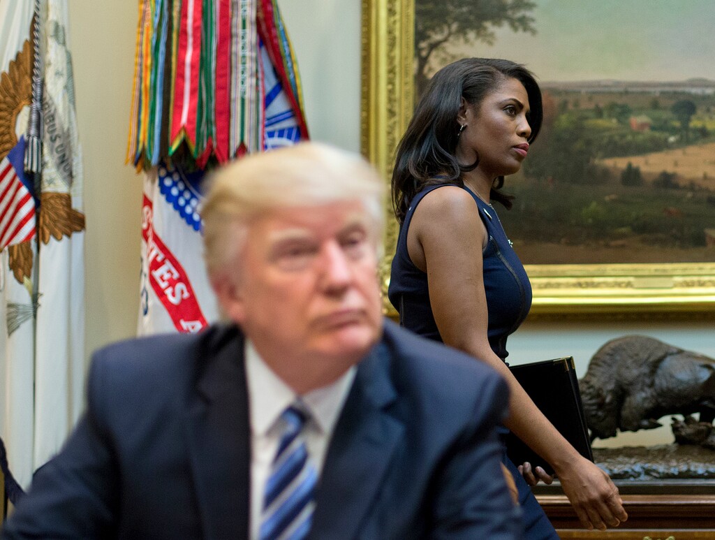 FILE - In this March 12, 2017 file photo, White House Director of communications for the Office of Public Liaison Omarosa Manigault, right, walks past President Donald Trump during a meeting on healthcare in the Roosevelt Room of the White House in Washington. Manigault Newman, who was fired in December, released a new book "Unhinged," about her time in the White House. (AP Photo/Pablo Martinez Monsivais, File)