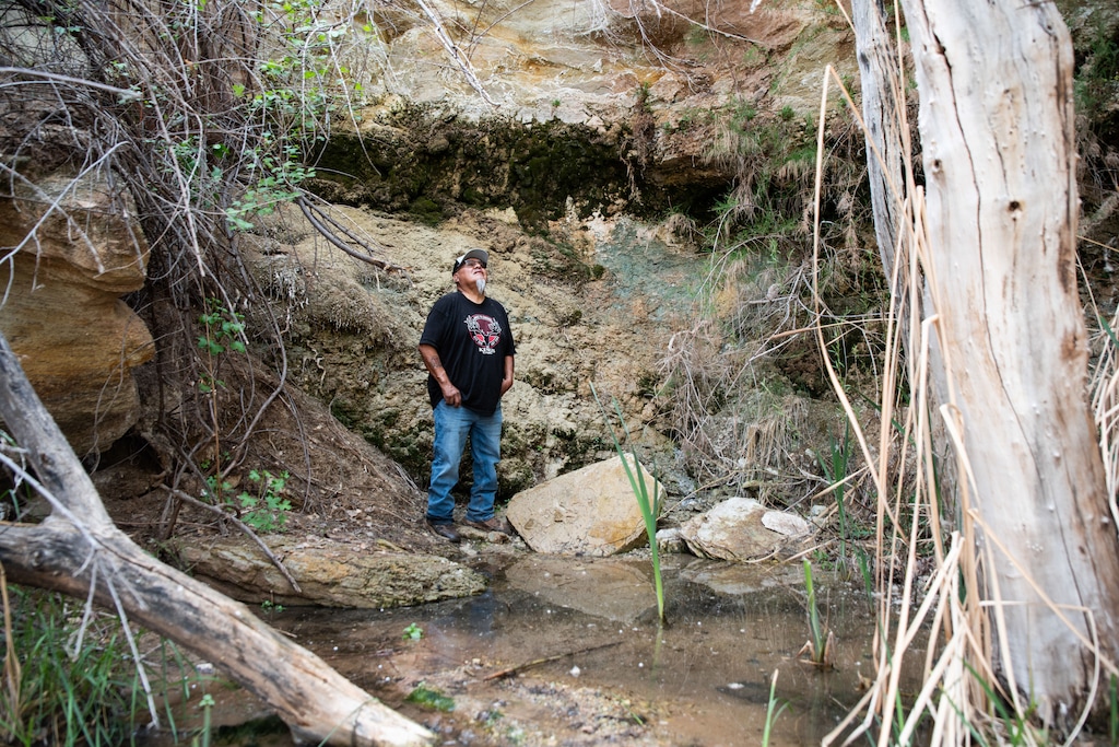 (Melissa Bailey for KFF Health News) Malcolm Lehi stands at Entrance Spring, where in the late 2000s elevated levels of radionuclides were linked to the nearby White Mesa Mill.