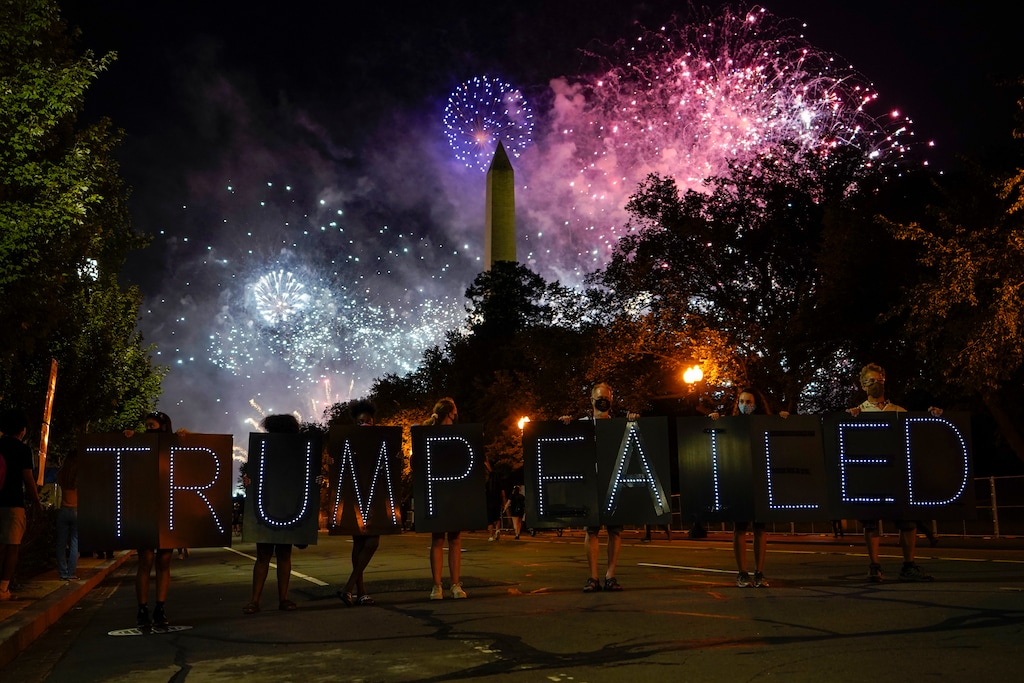 (Carolyn Kaster | AP file photo)  Protesters hold a lighted sign as fireworks light up the sky around the Washington Monument after President Donald Trump delivered his acceptance speech at the White House to the 2020 Republican National Convention, Thursday, Aug. 27, 2020.