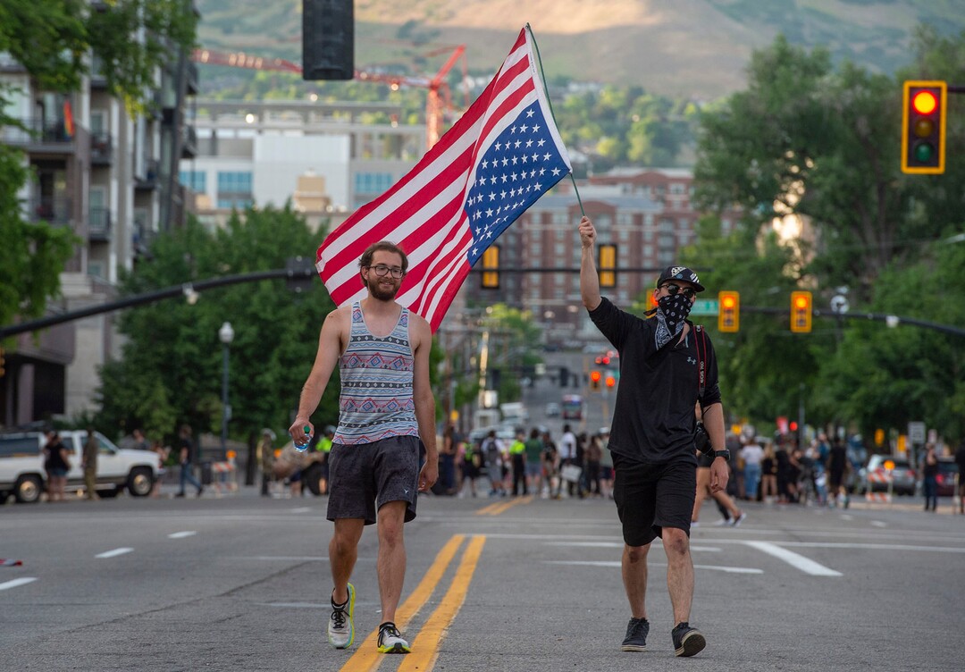 (Rick Egan  |  The Salt Lake Tribune)       Protesters wave a flag as they walk between checkpoints on 200 East, during a demonstration in Salt Lake City, Tuesday, June 2, 2020.