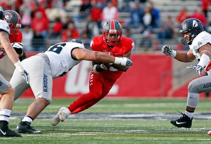 New Mexico running back Tyrone Owens (25) tries to avoid being sacked by Utah State nose guard Gasetoto Schuster (56) during the first half of an NCAA college football game in Albuquerque, N.M., Saturday, Nov. 4, 2017. (AP Photo/Andres Leighton)