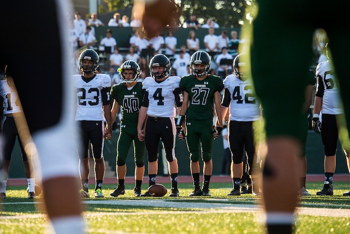 (Chris Detrick  |  The Salt Lake Tribune)    Members of the Hillcrest and Highland football teams hold hands during a remembrance for Hillcrest football coach Cazzie Brown before the game at Hillcrest High School Friday, September 1, 2017. Cazzie Brown passed away Sunday night after spending four days in the hospital. According to a family representative, Brown was brought to the emergency room Wednesday for complications with his thyroid. The doctors found that he had contracted meningitis, and later received a preliminary positive after being tested for West Nile virus. 