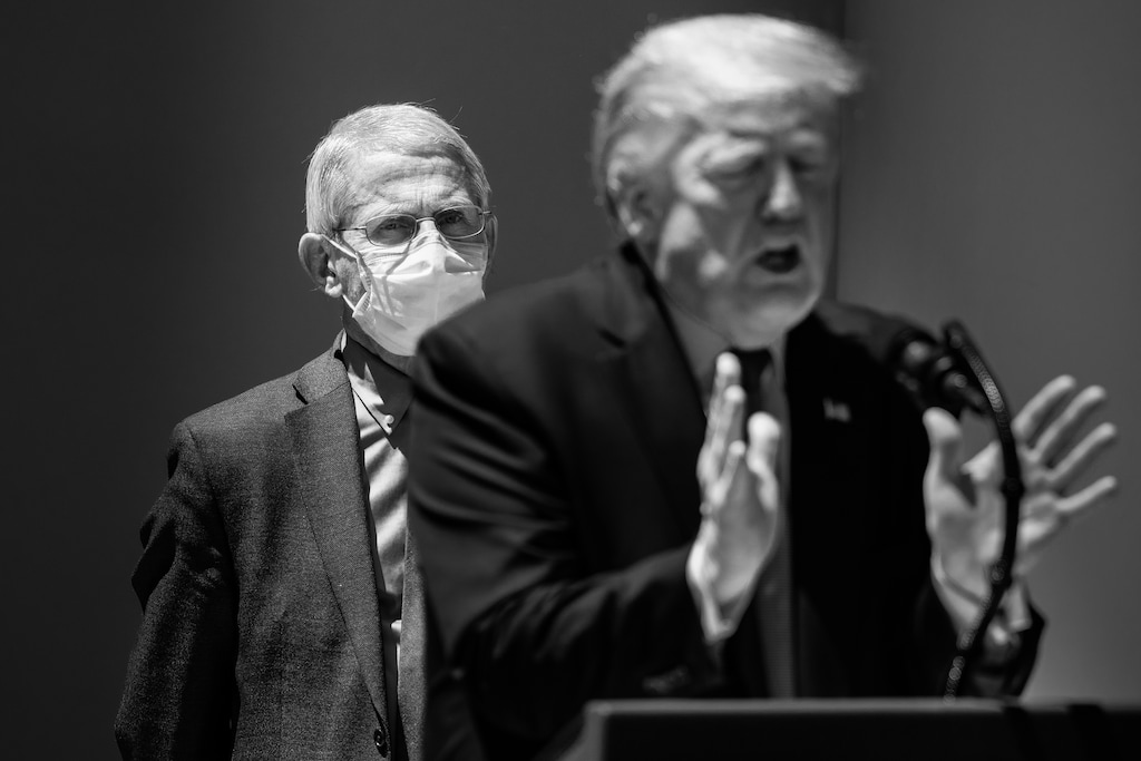 (Samuel Corum | The New York Times)
Dr. Anthony Fauci, the nation’s leading infectious disease specialist, looks on as President Donald Trump speaks to reporters at the White House on May 15, 2020. "The vaccine debate is the latest example of how our coronavirus choices are inescapably political," writes New York Times opinion columnist Ross Douthat.