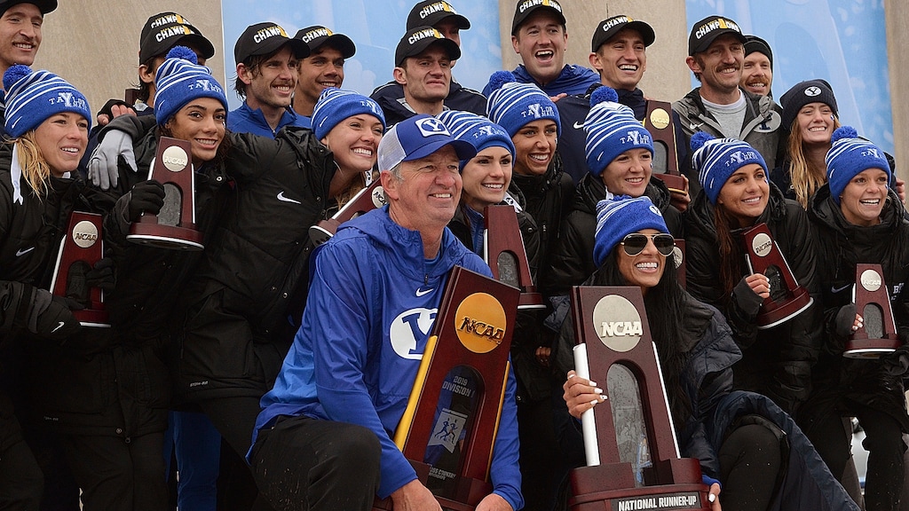 Brigham Young University men's cross country coach Ed Eyestone and women's coach Diljeet Taylor pose with their National Champion and National Runner-Up trophies, respectively, on the awards podium with their runners on Saturday, Nov. 23, 2019 after the NCAA Div. I Cross Country Championships at the Lavern Gibson Championship Cross Country Course in Terre Haute, Ind. (Joseph C. Garza/Tribune-Star via AP)