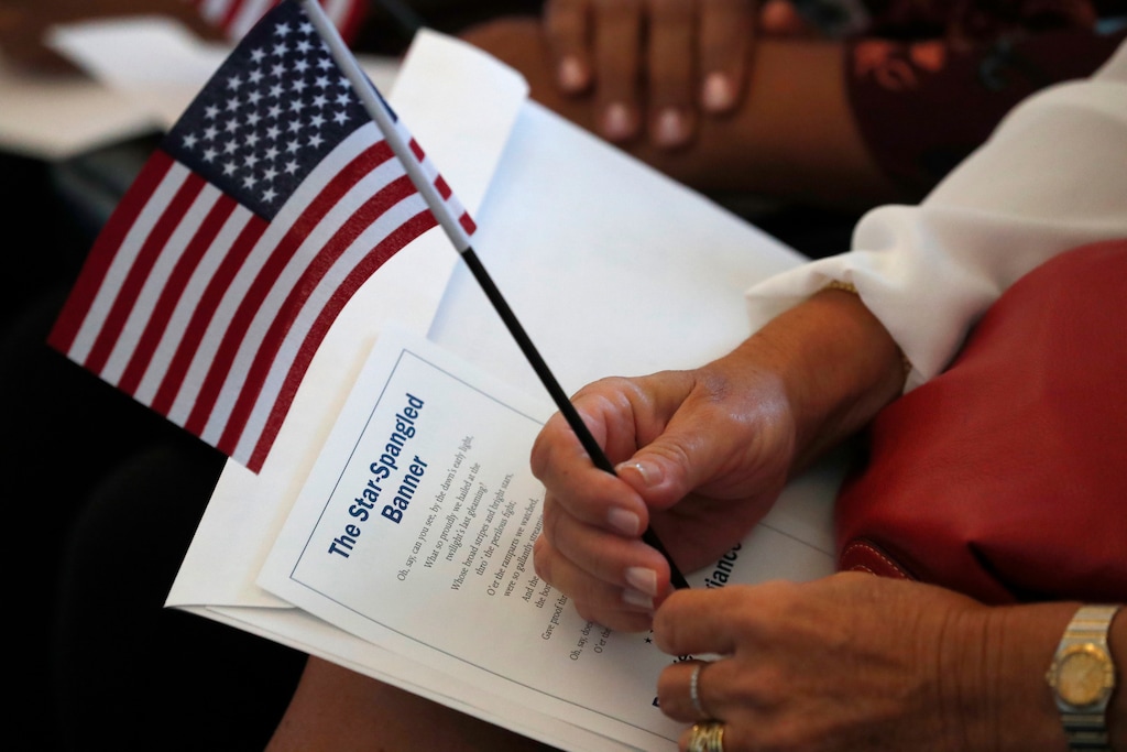 (Wilfredo Lee | AP File Photo) In this Aug. 16, 2019 photo a citizen candidate holds an American flag and the words to The Star-Spangled Banner before the start of a naturalization ceremony at the U.S. Citizenship and Immigration Services Miami field office in Miami.