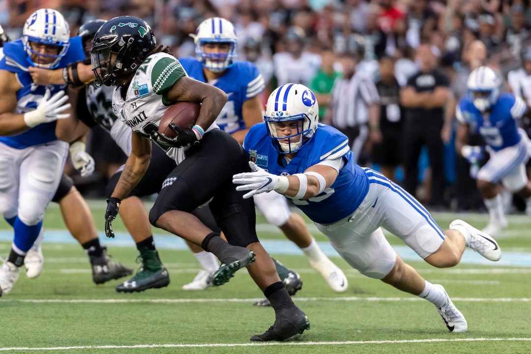 Hawaii running back Miles Reed (26) is tackled from behind by BYU linebacker Payton Wilgar, right, during the second half of the Hawaii Bowl NCAA college football game Tuesday, Dec. 24, 2019, in Honolulu. (AP Photo/Eugene Tanner)
