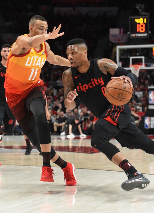 Portland Trail Blazers guard Damian Lillard, right, drives to the basket on Utah Jazz guard Dante Exum during the first half of an NBA basketball game in Portland, Ore., Wednesday, April 11, 2018. (AP Photo/Steve Dykes)