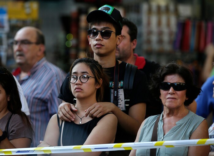 People stands behind police tape on a street in Barcelona, Spain, Thursday, Aug. 17, 2017. Police in the northern Spanish city of Barcelona say a white van has jumped the sidewalk in the city's historic Las Ramblas district, injuring several people. (AP Photo/Manu Fernandez)