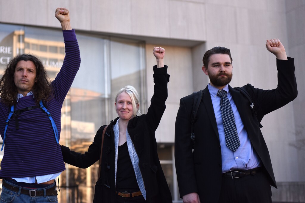 Brittne Lawson, center, Alexei Wood, left, and Oliver Harris raise their arms after receiving a not guilty verdict in the the first of the presidential inauguration riot trials on Dec. 21, 2017. (Michael Robinson Chavez/The Washington Post)