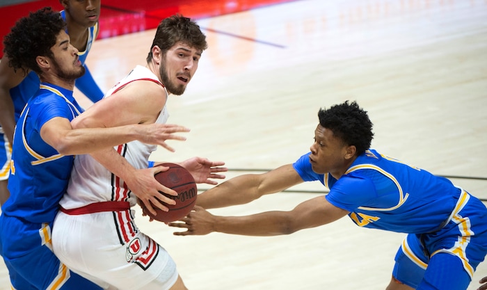 (Rick Egan | The Salt Lake Tribune) Utah Utes forward Riley Battin (21) tried to get a shot off, as UCLA Bruins guard Johnny Juzang (3) and UCLA Bruins guard Jaylen Clark (0) defend, in PAC-12 basketball action at the Jon M. Huntsman Center, on Thursday, Feb. 25, 2021.