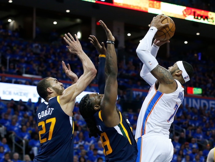 Oklahoma City Thunder forward Carmelo Anthony, right, goes up for a shot as Utah Jazz center Rudy Gobert (27) and forward Jae Crowder (99)stad defend in the first half of Game 1 of an NBA basketball first-round playoff series in Oklahoma City, Sunday, April 15, 2018. (AP Photo/Sue Ogrocki)