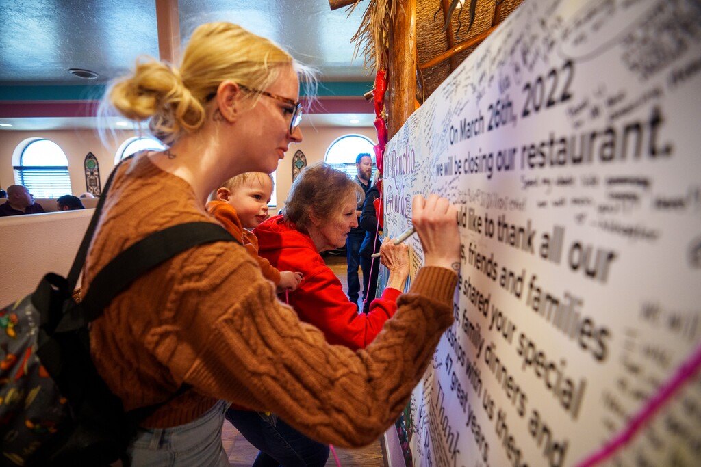 (Trent Nelson  |  The Salt Lake Tribune) Aubry Mix (with her grandmother Rae Jordison and holding her child Sullivan) signs a farewell banner at El Rancho Grande in Kearns, which is closing after nearly 50 years in business. The line of people waiting for tables went all the way outside on Thursday, March 24, 2022.