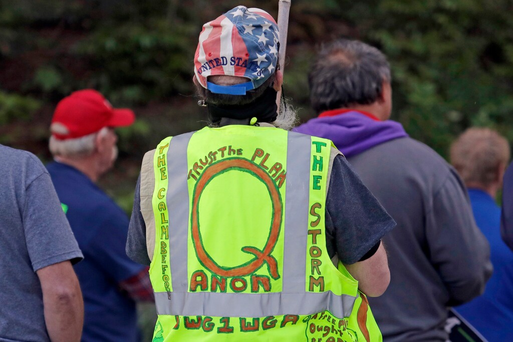 (Ted S. Warren | AP file photo) In this May 14, 2020, file photo, a person wears a vest supporting QAnon at a protest rally in Olympia, Wash.