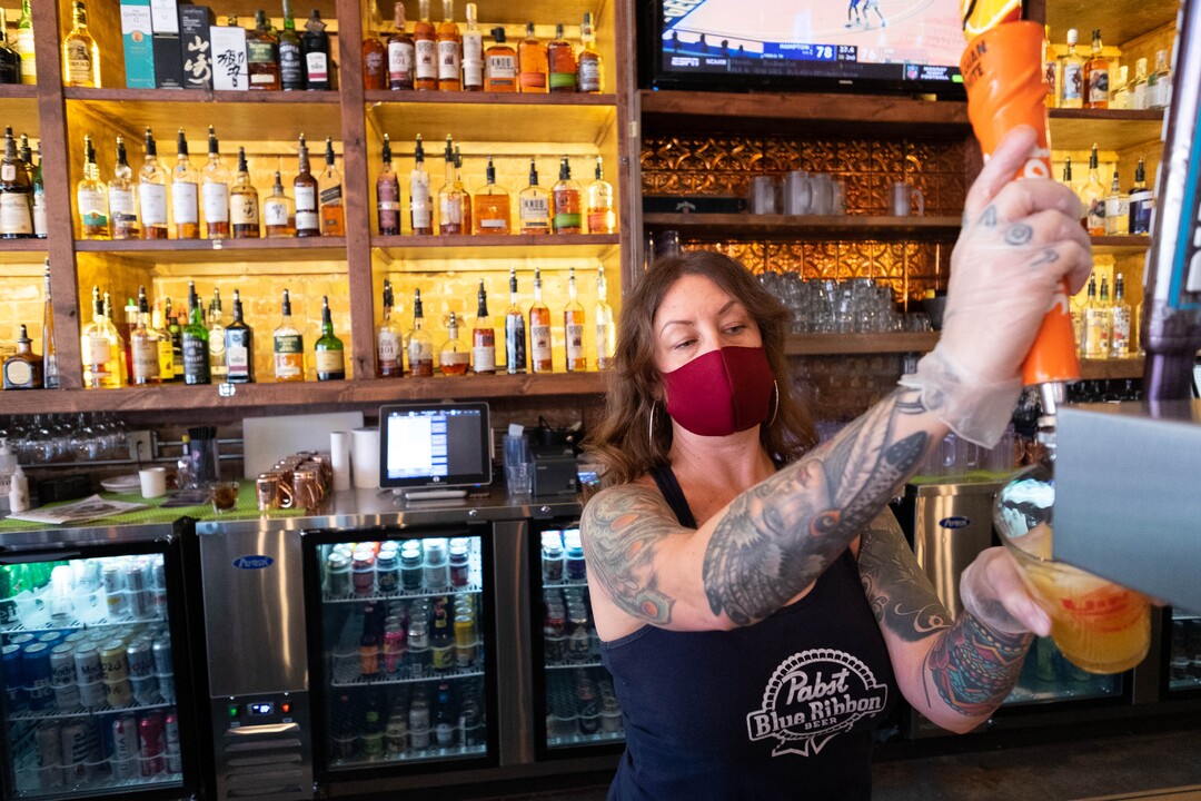 (Francisco Kjolseth  | The Salt Lake Tribune) Robin Brown pours drinks at the Green Pig Pub in Salt Lake City during the slow lunch hour on Thursday, Dec. 3, 2020. The owners of 25 different Utah bars — including the Green Pig Pub —  have sent a letter to Gov. Gary Herbert protesting the state health order that requires alcohol service to stop at 10 p.m They say the restriction is devastating the bar industry in Utah and has caused hundreds of thousands of dollars in lost  revenue, hurt employees, and could force many to close.