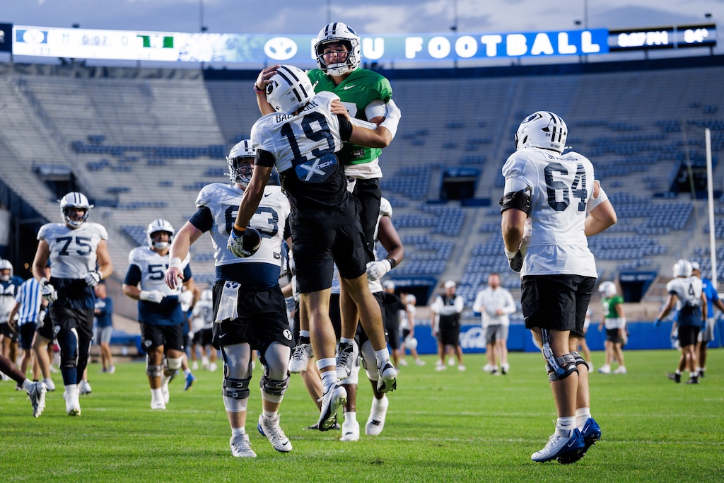 (BYU Athletics) BYU quarterback Bear Bachmeier, center in green, celebrates with his brother, wide receiver Tiger Bachmeier, during a scrimmage at LaVell Edwards Stadium during 2025 fall football camp.