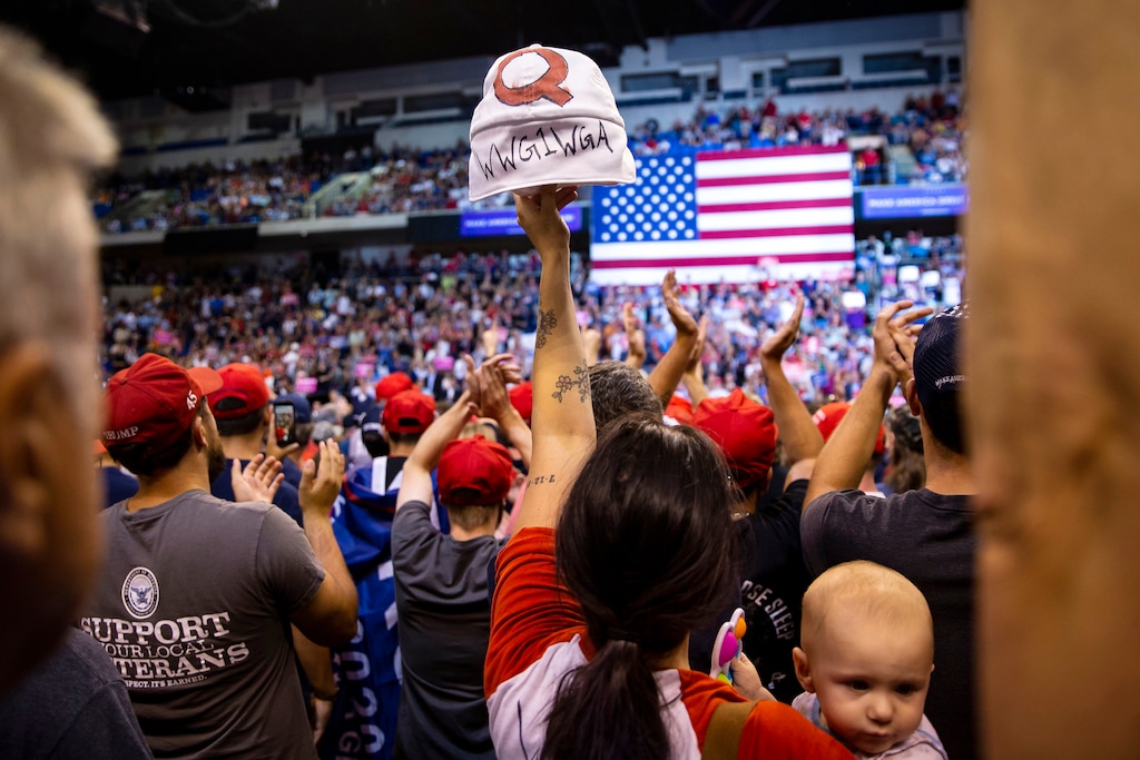 FILE -- A woman holds up a hat with a Q on it, denoting QAnon, during a rally with President Donald Trump in Avoca, Penn., Aug. 2, 2018. Fans of the pro-Trump conspiracy theory are clogging anti-trafficking hotlines, infiltrating Facebook groups and raising false fears about child exploitation. (Al Drago/The New York Times)