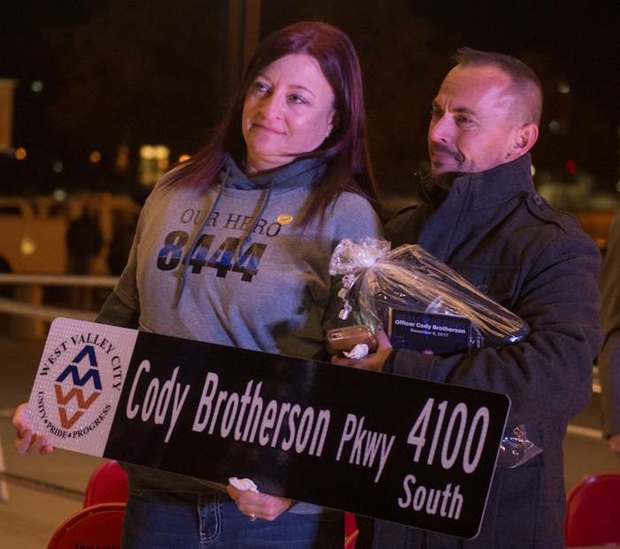 (Rick Egan  |  The Salt Lake Tribune)  Jenny and Jeff Brotherson, parents od Cody Brotherson, hold a street sign after  a memorial ceremony at Fairbourne Station Plaza in West Valley City, in remembrance of their son Cody, who was killed in the line of duty one year ago today. It was announced tonight that West Valley will name 4100 South Cody Brotherson Parkway. Monday, November 6, 2017.