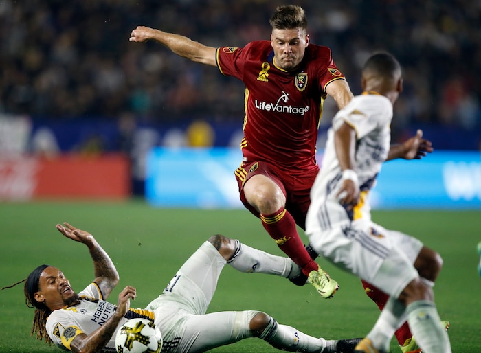 Real Salt Lake defender David Horst, center, leaps over the tackle by Los Angeles Galaxy midfielder Jermaine Jones (13) to get to the ball during the second half of an MLS soccer game in Carson, Calif., Saturday, Sept. 30, 2017. (AP Photo/Alex Gallardo)