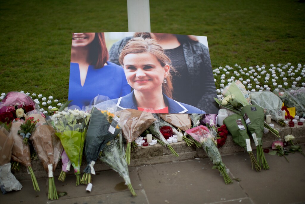 An image and floral tributes for Jo Cox, the 41-year-old British Member of Parliament shot to death yesterday in northern England, lie placed on Parliament Square outside the House of Parliament in London, Friday, June 17, 2016. The mother of two young children was shot to death Thursday afternoon in her constituency near Leeds. A 52-year-old man has been arrested but has not been charged. He has been named locally as Tommy Mair. (AP Photo/Matt Dunham)