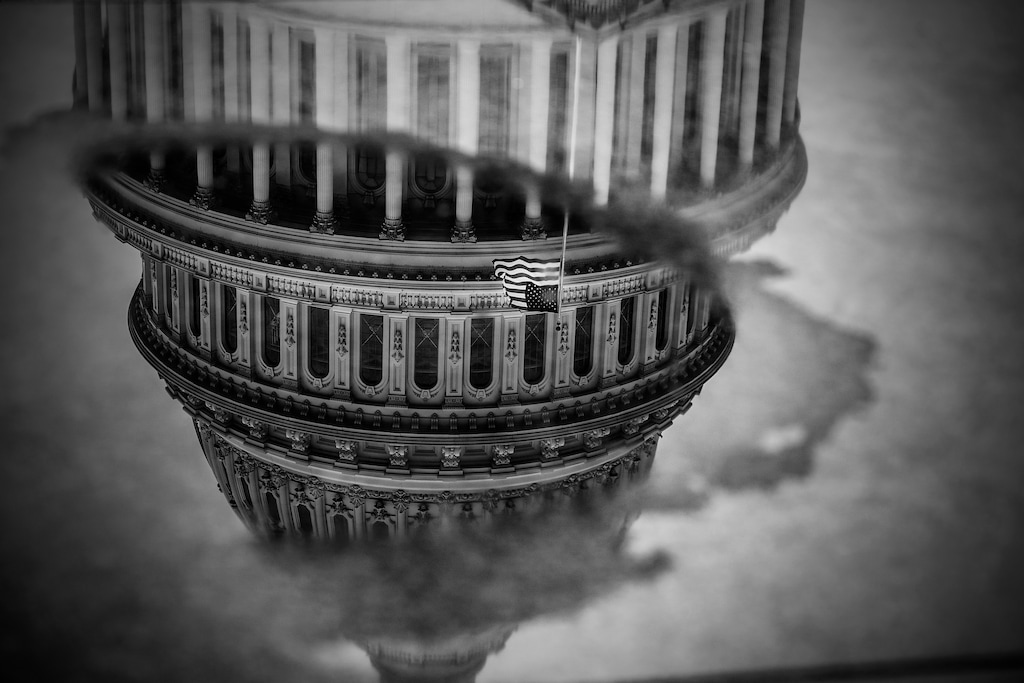 The U.S. Capitol is seen reflected in a puddle in Washington in January 2021. (Mark Peterson/The New York Times)