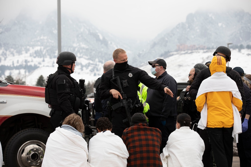 (Eliza Earle | The New York Times) Safety officials help people outside of the Boulder King Soopers grocery store after a shooting that killed multiple people in Boulder, Colo., on Monday, March 22, 2021.