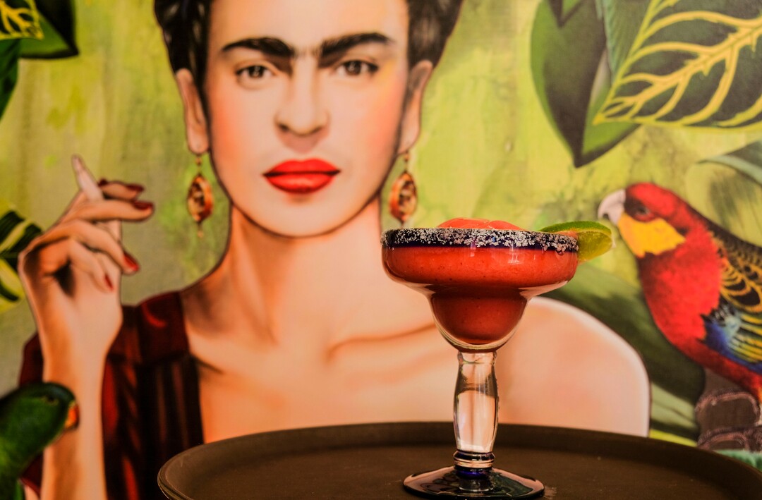 (Leah Hogsten  |  The Salt Lake Tribune) ARio Grande Cafe's strawberry frozen margarita in front of a painting of Frida Kahlo.  Salt Lake City's popular Rio Grande Cafe, which has been closed since March due to the pandemic and the earthquake, has moved to its new location near the University of Utah on 1300 East, Dec. 29, 2020.