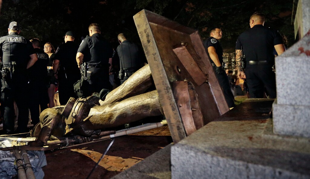 Police stand guard after the confederate statue known as Silent Sam was toppled by protesters on campus at the University of North Carolina in Chapel Hill, N.C., Monday, Aug. 20, 2018. (AP Photo/Gerry Broome)