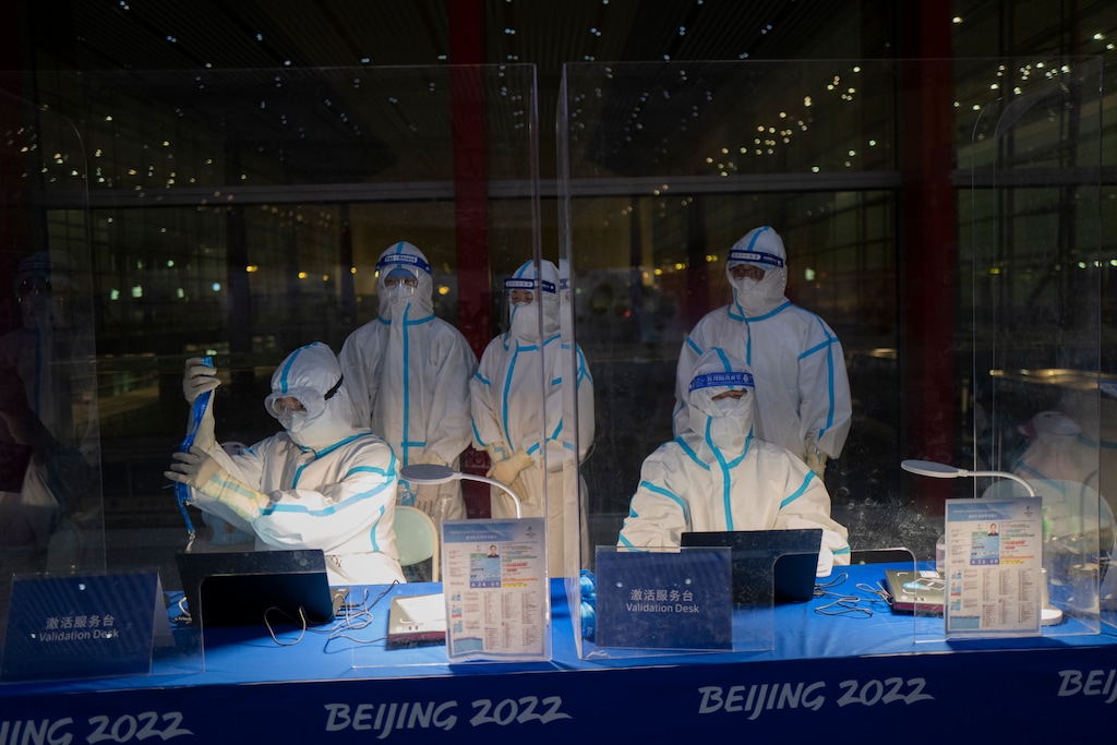 (Jae C. Hong | AP) Olympic workers in hazmat suits work at a credential validation desk at the Beijing Capital International Airport ahead of the 2022 Winter Olympics in Beijing, Monday, Jan. 24, 2022.