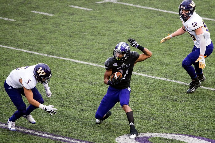 (Chris Detrick  |  The Salt Lake Tribune)  Weber State Wildcats running back David Jones (21) runs past Western Illinois Leathernecks defensive back Aaron Diggs (5) and Western Illinois Leathernecks linebacker Riggs Baxter (58) during the game at Stewart Stadium Saturday, November 25, 2017.  