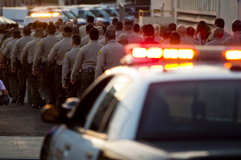 (Damian Dovarganes | AP Photo) Los Angeles County Sheriff's deputies walk in a procession behind a coroner's van transporting the body of fallen Deputy Joseph Gilbert Solano to the Los Angeles County Department of Medical Examiner-Coroner after a news conference announcing his death, Wednesday, June 12, 2019, in Los Angeles. Solano, who had been on life support, died Wednesday afternoon after being shot in an off-duty attack at a fast-food restaurant on Monday.