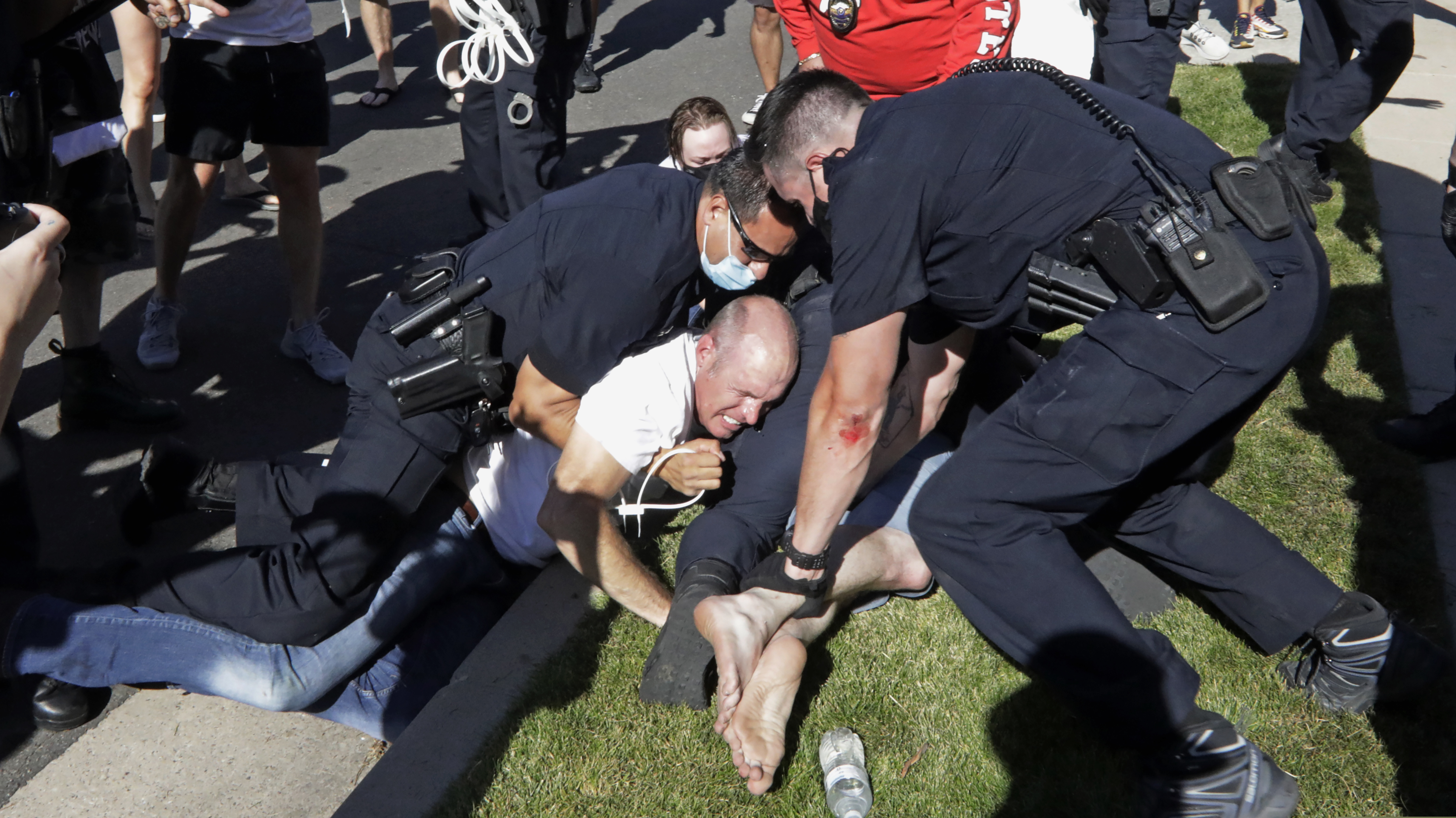 (Rick Bowmer | AP) Aaron James is arrested by Cottonwood Heights Police during a march Sunday, Aug. 2, 2020, in Cottonwood Heights, Utah. James was among eight people arrested by Cottonwood Heights Police in August. He is the father of Zane James, a 19-year-old white man who was shot and killed by a Cottonwood Heights Police officer in 2018 as he fled the scene of a robbery. Now, they are suing the city, claiming officers attacked the teen’s father and brother at a peaceful protest over his death last year.