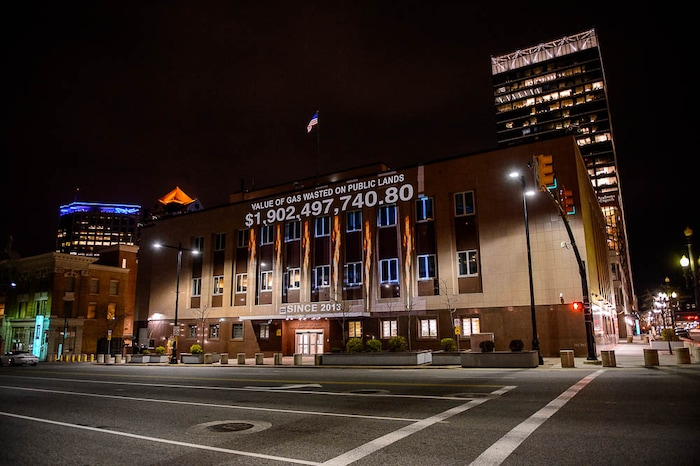 (Trent Nelson | The Salt Lake Tribune)
In a visual protest, Alliance for Better Utah projects the total dollar value of natural gas lost on public lands since 2013 due to venting, flaring, and leaking onto the side of Federal Reserve Building in Salt Lake City, Thursday April 5, 2018.