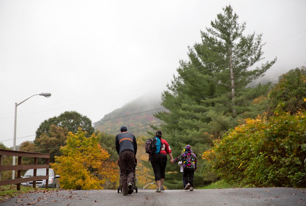 (David Goldman | The Associated Press) In this Oct. 16, 2014, file photo, an unemployed coal miner walks with his family on their way back to their apartment from the bus stop in Lynch, Ky. From drivers paying more for gas and families bearing heavier child care costs to workers still awaiting decent pay raises to couples struggling to afford a home, people throughout the economy are straining to succeed despite the economy’s gains.