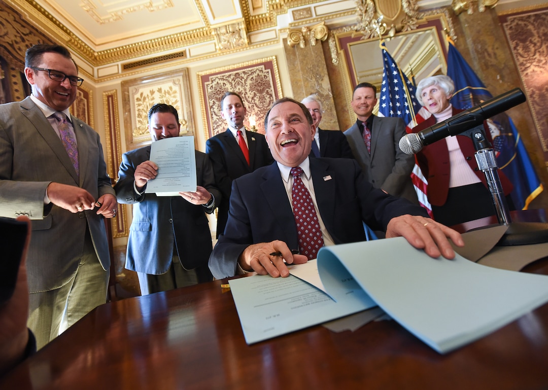 (Francisco Kjolseth  |  The Salt Lake Tribune)  Gov. Gary Herbert laughs after House speaker Greg Hughes, at left, make a snarky comment about the governor vetoing fewer bills if he gives away enough pens following his signing of H.B. 472 - Medicaid Expansion Revisions, at the Utah Capitol on Tuesday, March 27, 2018. The bill would expand Medicaid healthcare coverage to cover an additional 60,000 Utahns below the poverty line — pending approval from the federal government.