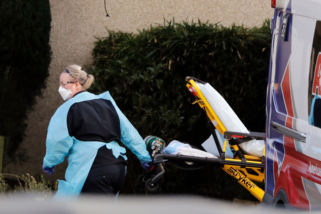 (Elaine Thompson | AP) An ambulance worker wears protective equipment as she wheels a stretcher into a nursing facility where more than 50 people are sick and being tested for the COVID-19 virus, Saturday, Feb. 29, 2020, in Kirkland, Wash.