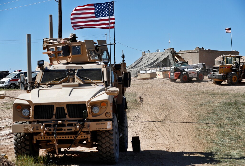 (Hussein Malla | The Associated Press) In this Wednesday, April 4, 2018 file photo, a U.S. soldier, left, sits on an armored vehicle behind a sand barrier at a newly installed position near the front line between the U.S-backed Syrian Manbij Military Council and the Turkish-backed fighters, in Manbij, north Syria. An American military official said Friday, Jan. 11, 2019 that the U.S.-led military coalition has begun the process of withdrawing troops from Syria.