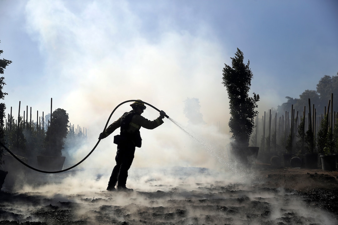 (Marcio Jose Sanchez | AP) Morgan Clark, a firefighter with the Oxnard Fire Dept., hoses down hot spots created by the Easy Fire on a farm Wednesday, Oct. 30, 2019, in Simi Valley, Calif.